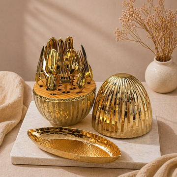 Gold-toned gift set featuring a spoon and fork holder with matching lid and tray, arranged on a beige surface with soft lighting and minimal decor for an elegant, premium look.